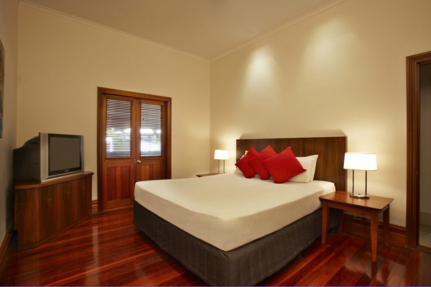 Bedroom Medium size White Wall Interior Also Wooden Flooring Furniture Scheme From White Bed Escorted By Three Red Pillows Also Wooden Night Tables Escorted By Sleeping Lamps Also Wooden Tv Case Style