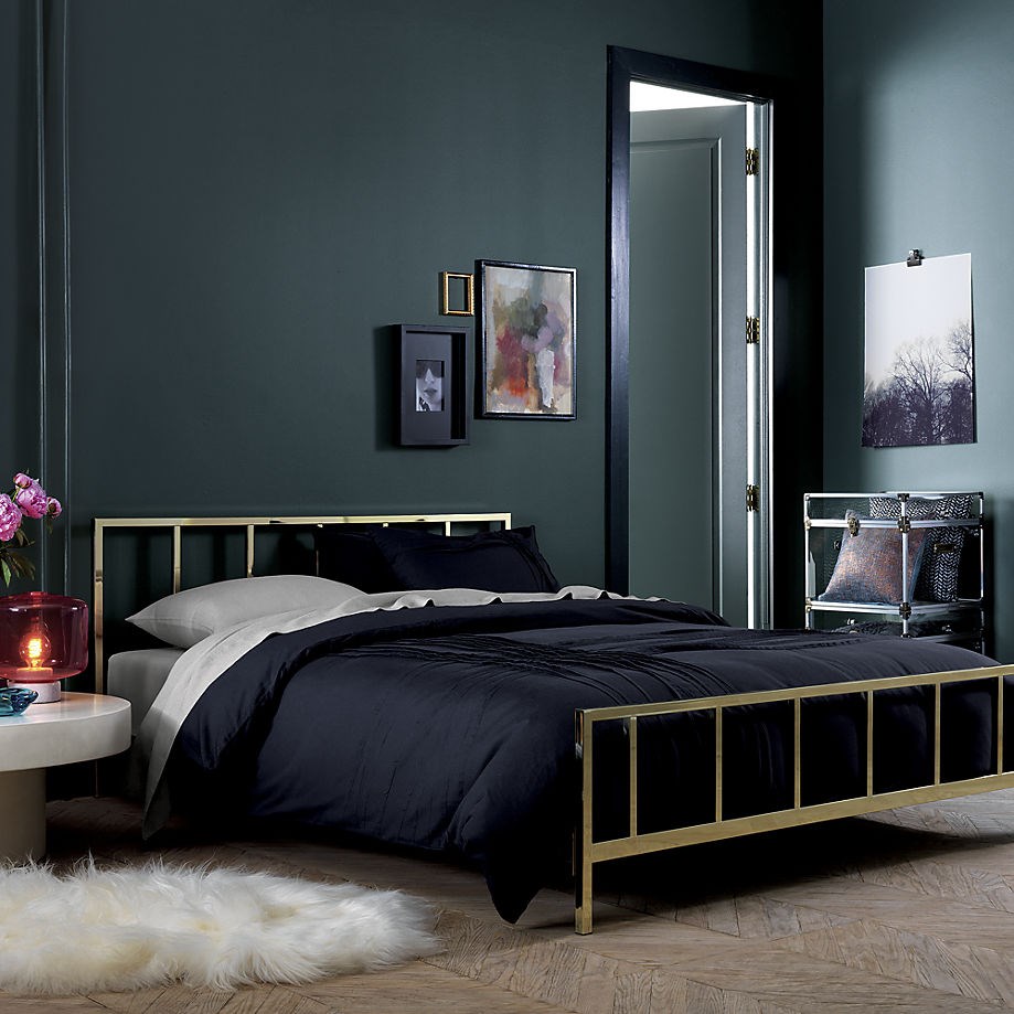 Black Bedding Set With Metal Frame Upon White Furry Rug Surrounded Dark Backdrop Bedroom