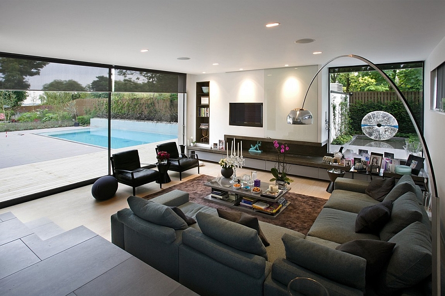 Open Spacious Grey Living Space With Curve Floor Lamp And Brown Patterned Area Rug Facing Outdoor Pool Interior Design