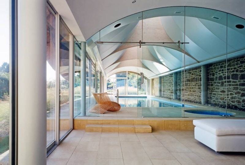 Stunning Indoor Pool Design Under Round Sloping Ceiling With Tan Chair Aside Concrete Deck Architecture